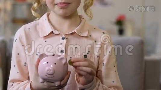 可爱的女孩把硬币放进储蓄罐，从小就有钱，特写镜头视频
