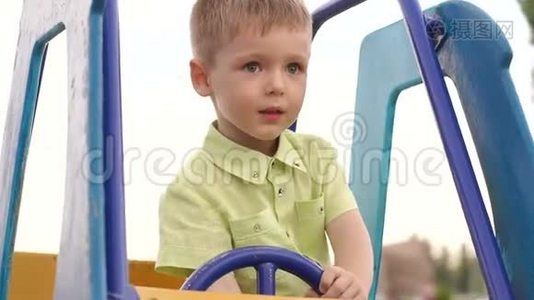 那个孩子坐在操场上一辆儿童`车的车轮前。视频