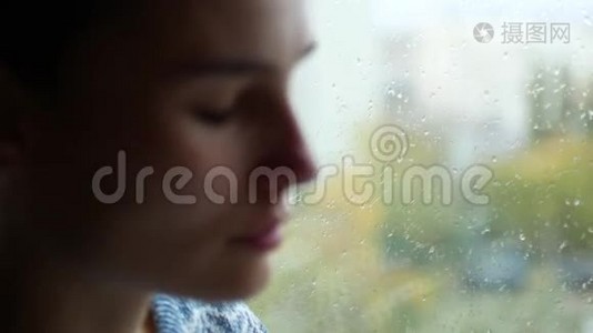 女人流鼻涕。一个小女孩坐在窗边，外面在下雨。抑郁视频