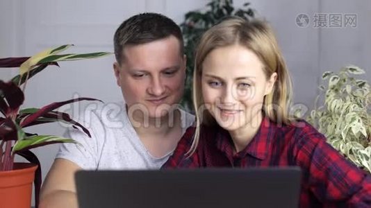 一对年轻夫妇正坐着笑着看着笔记本电脑屏幕视频