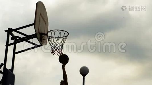 篮球运动员在运动场上用篮圈投掷球。 运动员在户外环形投掷球。 篮球比赛缓慢视频