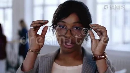 专业年轻的非洲经理商务女性调整眼镜的特写肖像，在现代办公室摆姿势。视频