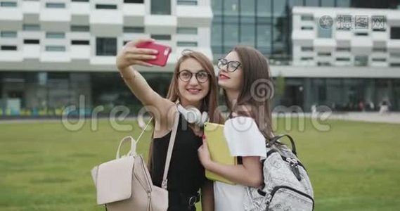 两个美丽的无忧无虑的女孩用智能手机自拍。 女人做滑稽的脸。 最好的朋友拍照视频
