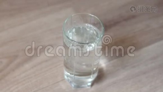 一个女人把水倒进木桌上的玻璃里的特写镜头。视频