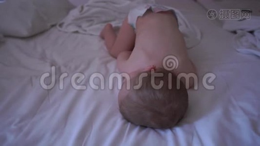 一个穿着尿布的裸体婴儿正在床上缓慢地睡觉视频