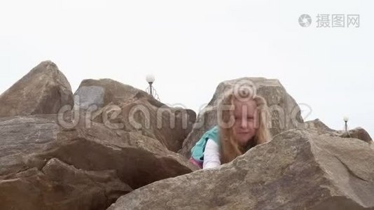 女孩学龄前儿童在海滨的大石头上玩耍。视频