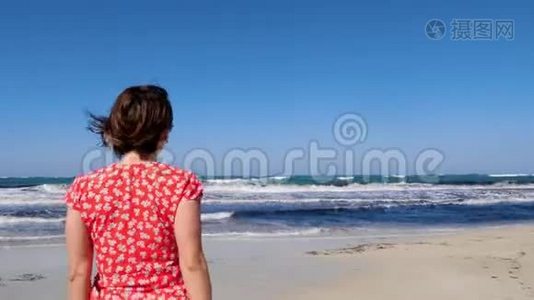 年轻微笑的女人邀请一个男人跟随她走向大海。 强烈的波浪撞击海滩。 红色连衣裙和太阳镜视频