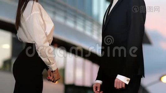 在商业大厦的室外，商务男性和商务女性之间握手。视频