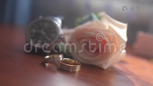 结婚饰品。 腕表，金色戒指，一束美丽的花束在棕色纹理的桌子上。 新娘的概念视频