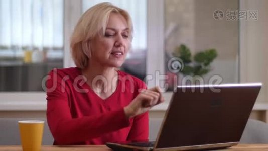 在一个舒适的房间里，一个年轻的白种人女人在笔记本电脑上打了一个视频电话，在室内愉快地交谈视频
