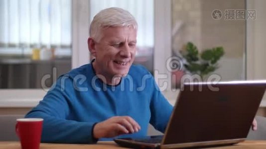 在一间舒适的公寓里，一个年轻的白种人在笔记本电脑上打字，笑得很开心视频
