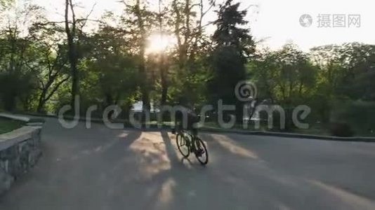骑自行车的人骑在公园路上。 骑着自行车下山的瘦小的骑车人。 慢动作视频