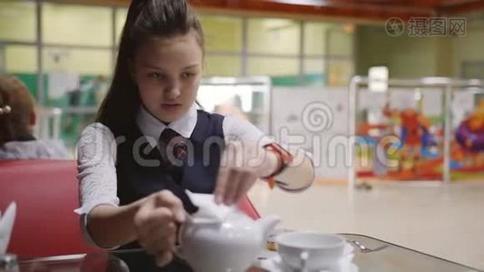 在学校食堂休息。 一个十几岁的女孩把茶从水壶里倒入杯里。视频