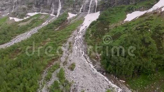 空中观景无人机拍摄到几条瀑布从陡峭的大山岩上流下来，这些岩石被郁郁葱葱地包围着视频