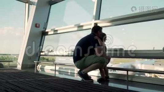 父子俩透过玻璃窗看着飞机.. 在机场和婴儿一起旅行视频