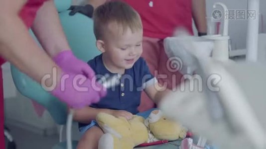 可爱的小男孩坐在牙医办公室的椅子上玩医疗工具。 免费儿童探访视频