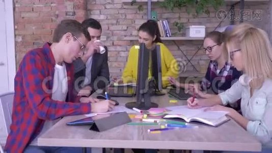 活跃的年轻上班族在笔记本上写着有创意的笔记，在现代办公室的桌子上贴着彩色贴纸视频