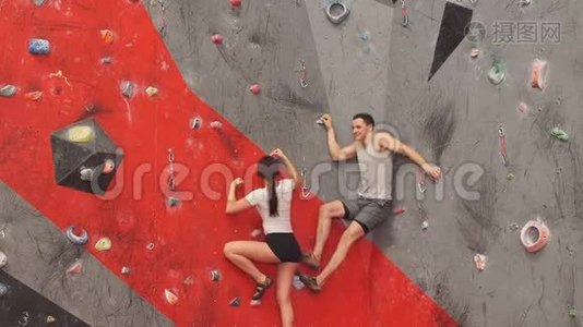 肌肉男帮助他的女朋友爬墙。视频