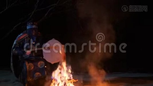 萨满坐在火旁，手里拿着一只手鼓。视频