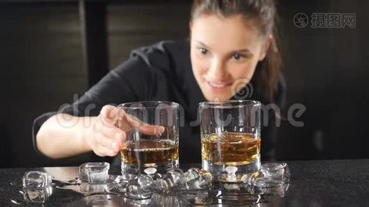 夜总会里的夜生活。 女酒保在酒杯里准备酒精鸡尾酒，使冰块缓慢运动。 冰冰视频
