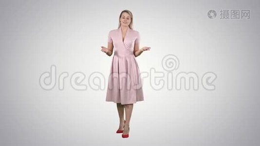金发女人穿着粉红色的衣服，在渐变背景上和镜头交谈。视频