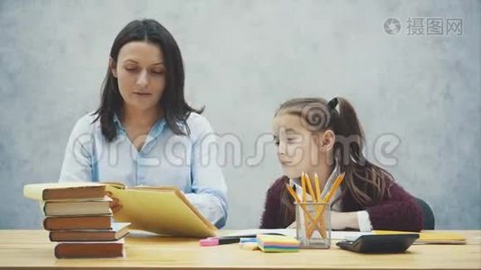 坐在桌子旁的漂亮女学生。 在家和她妈妈做作业。视频