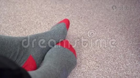 双脚穿着红灰色袜子在浅棕色地毯上相互摩擦视频