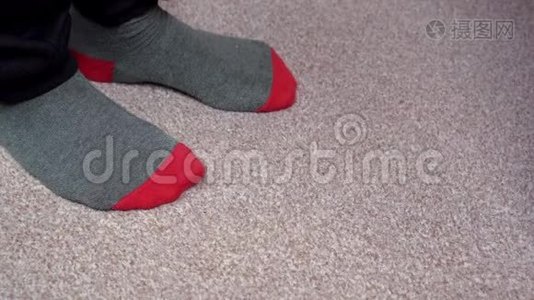 穿着红灰色袜子的脚在浅棕色地毯上互相摩擦。 站立站立视频