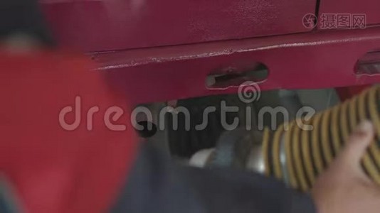 一个服务站工作人员在汽车的排气管上放一根管子来测量烟雾和废气。视频