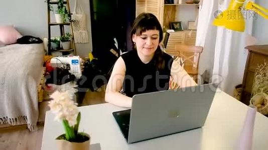 女人坐在一张桌子旁，用笔记本电脑工作。视频