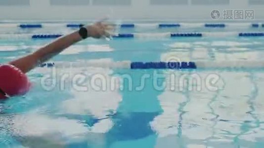 特写镜头。 熟练的女游泳运动员在游泳池里训练。 她爬行或爬行，用手划。 她是视频