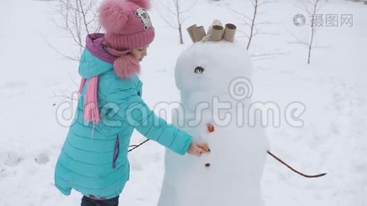 小女孩装饰雪人。 冬季运动会。视频