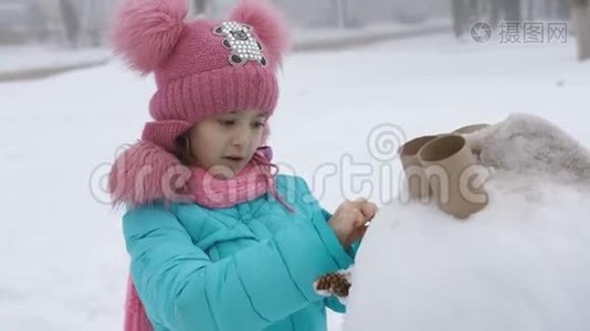 小女孩装饰雪人。 冬季运动会。视频