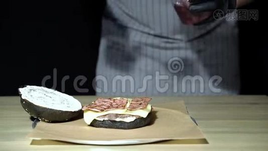 厨师的双手用烟熏培根和樱桃做一个美味的黑汉堡。视频