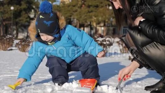 小男孩和他妈妈在雪地公园玩得很开心。 快乐的家庭在冬天玩雪。 活跃的冬季游戏。视频