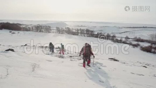 在滑雪杆的帮助下，一个陡峭的雪坡沿着一群登山者往下滑，他们轻轻地在滑雪道上留下一条小径视频