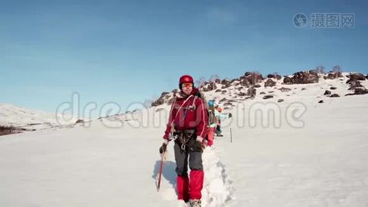 登山者站着，威严地看着他的团队走过的道路。 他身后站着他友好的球队和白雪视频