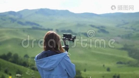 年轻的女人拿着相机看大自然。 山区的旅游女摄影师。 慢动作视频