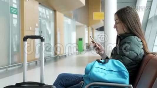 机场里的女人在等她的航班，有些东西在看智能手机。视频