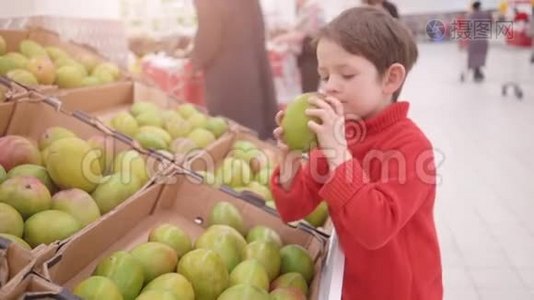 有趣的小男孩在超市的家庭购物中从盒子里摘芒果视频