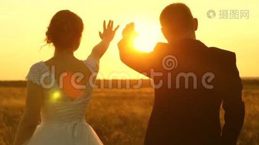 一男一女在夕阳下用手秀出一颗心。浪漫之旅中的恋人。团队合作视频