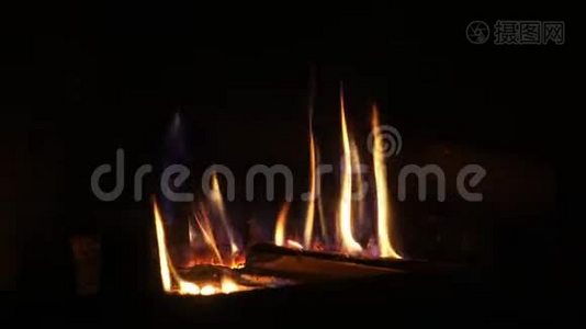 在舒适的砖制壁炉中，用橙色火焰缓慢燃烧的木头上拍摄了令人满意的特写镜头视频