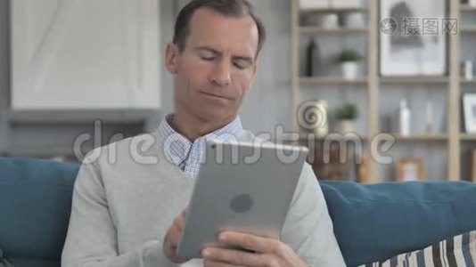 中老年人在沙发上放松时使用平板电脑视频