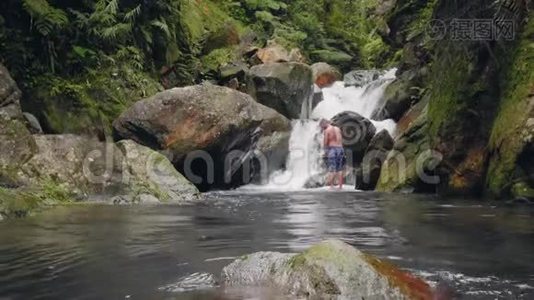 在热带雨林的热带瀑布景观上旅行的人。 游客站在背景流动的山河上视频