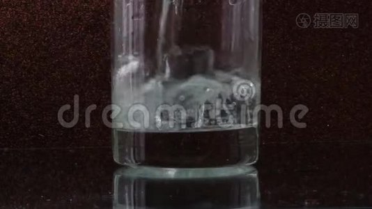 玻璃透明玻璃中的冰块和倒入黑色背景的水视频