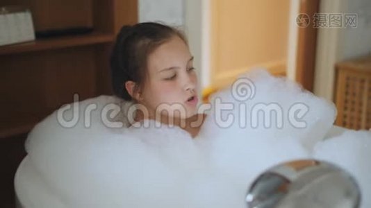 一个十几岁的女孩在浴缸里满是泡沫放松。视频