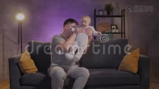 一个男人在舒适的公寓里和他的孩子在沙发上玩耍。 爸爸和宝宝很开心视频