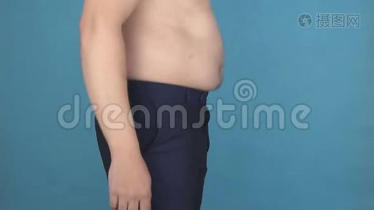 一个腹部赤裸的年轻人跳起来，摇动脂肪褶皱和腹部脂肪团，营养不良的概念视频