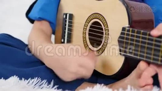 一个孩子的手紧紧地握着吉他的弦。 一个孩子弹一个孩子`吉他。 音乐。 概念视频