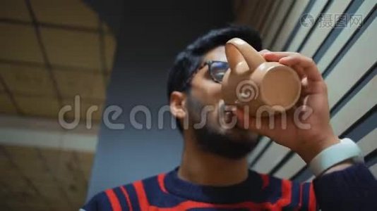特写镜头，下面是一个喝咖啡看智能手机的印度男人视频